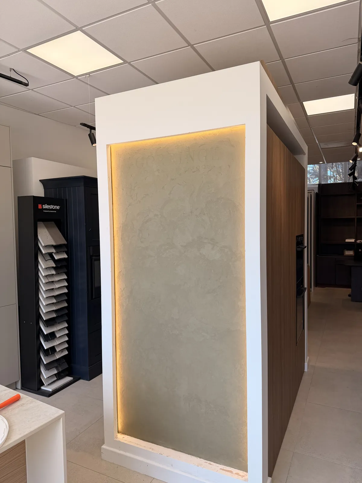Backlit microcement feature panel with Gorringe Kitchens and Bathrooms lettering, in their showroom