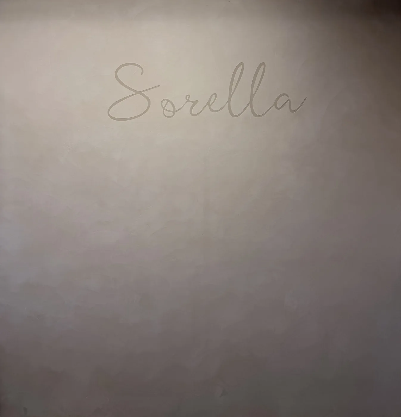 Sorella wordmark worked into a commercial microcement feature wall, low light