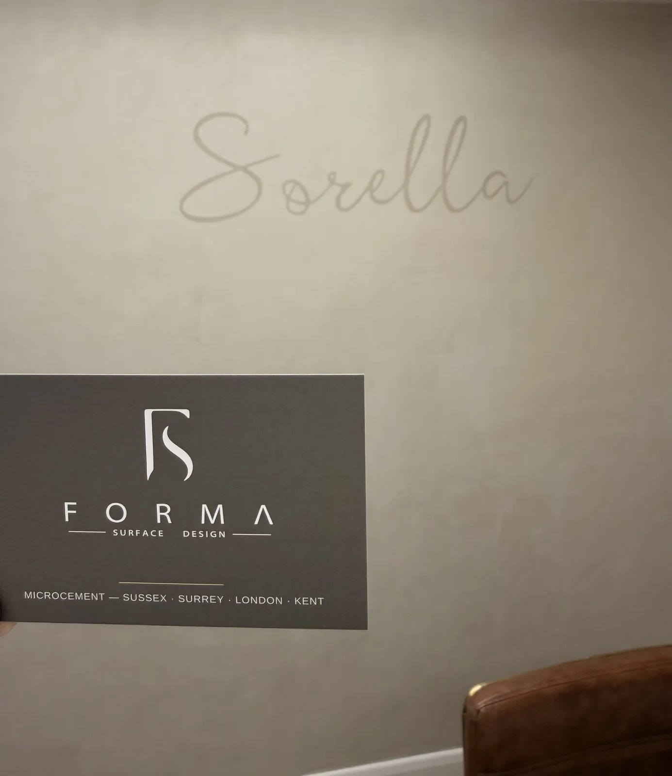 Forma business card held up against the finished Sorella feature wall