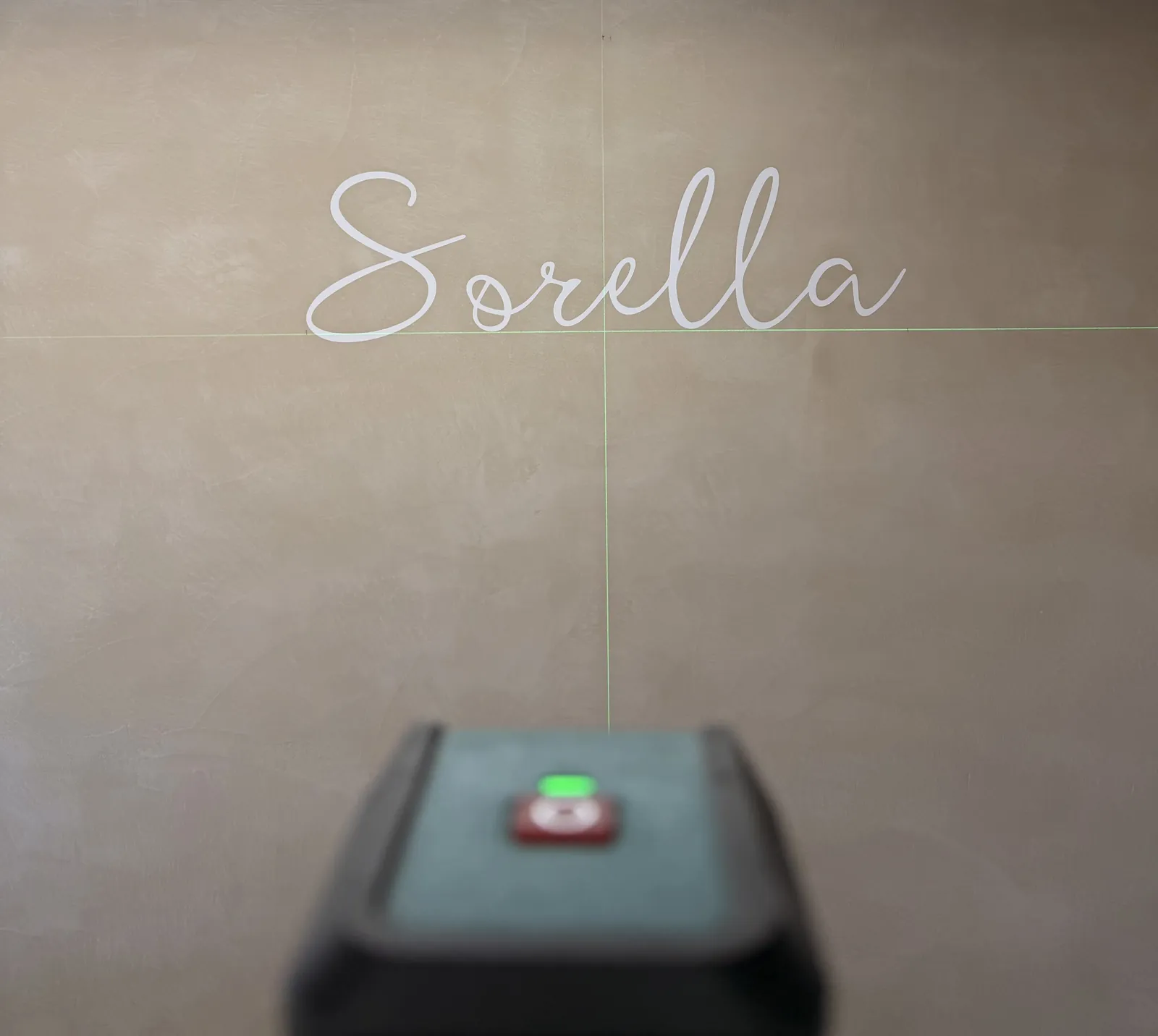 Laser level setting out the Sorella lettering on a finished microcement wall
