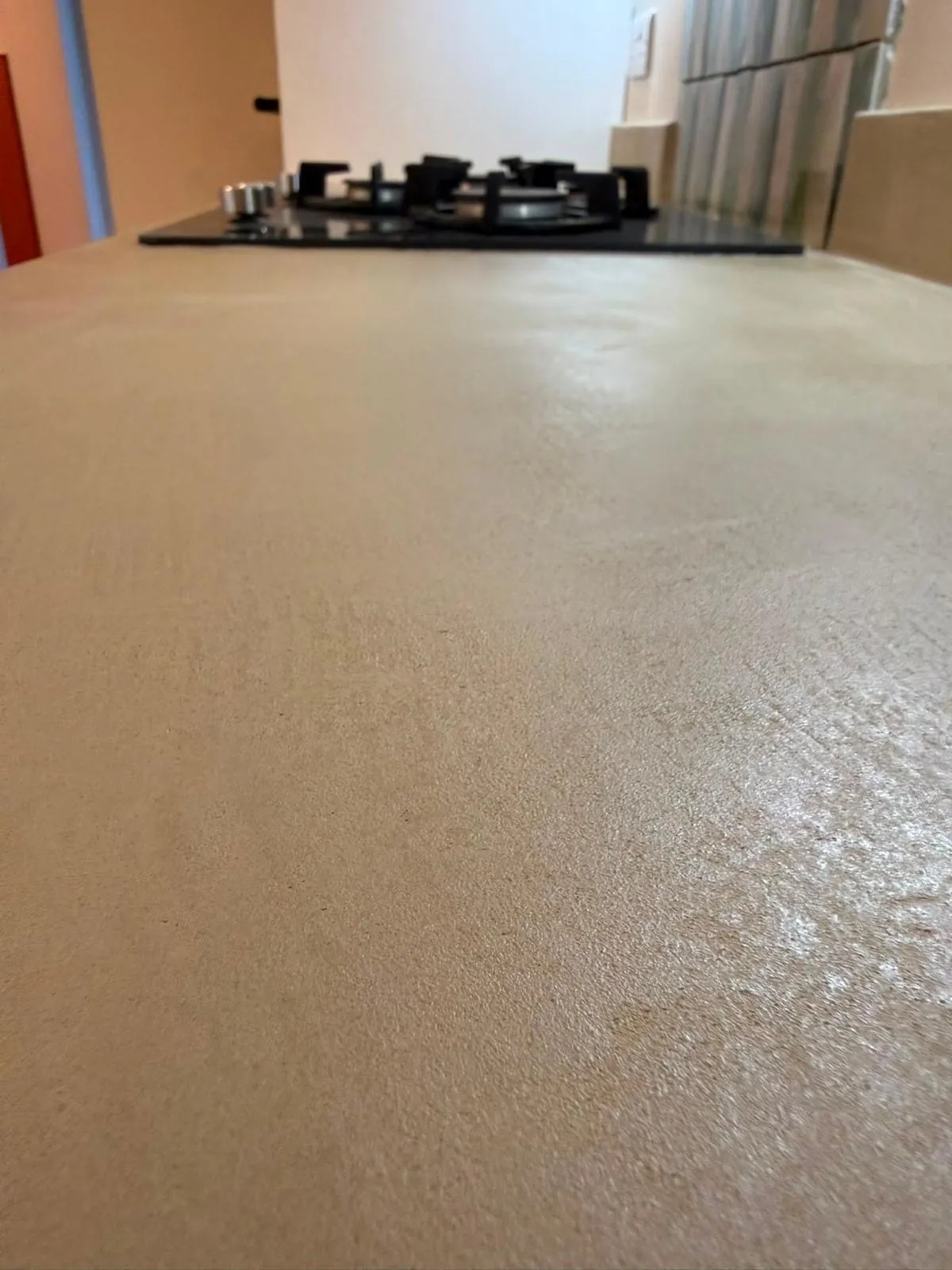 Microcement worktop at eye level, running seamlessly up to a gas hob